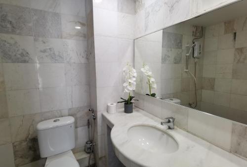 ein Badezimmer mit einem WC, einem Waschbecken und einem Spiegel in der Unterkunft Luï Luï Comfy Condo in Great Location in Kuah
