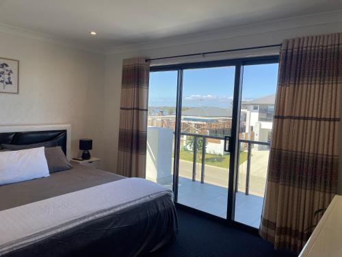 a bedroom with a bed and a balcony with a view at Waterside Holiday Home in Redcliffe