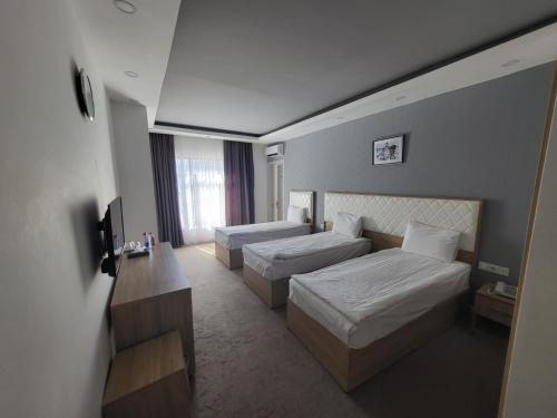 a hotel room with two beds and a television at Baku Tour Hotel & Hostel in Baku