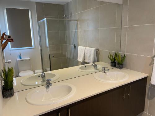 uma casa de banho com 2 lavatórios e um espelho grande em Waterside Holiday Home em Redcliffe