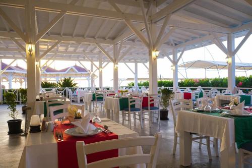 een restaurant met witte tafels en stoelen en groene en witte tafels bij Crystal Flora Beach Resort - Ultimate All Inclusive in Beldibi
