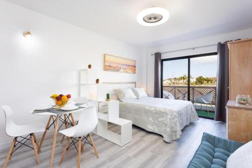 1 dormitorio blanco con 1 cama, mesa y sillas en Precioso apartamento en el Sur de Tenerife, en San Miguel de Abona