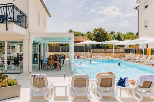 a swimming pool with chairs and people in a pool at Cool Šilo Appartement Resort in Šilo