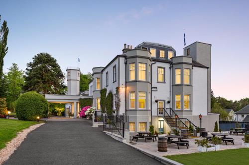 a large white house with benches in front of it at Wyndham Duchally Country Estate in Auchterarder