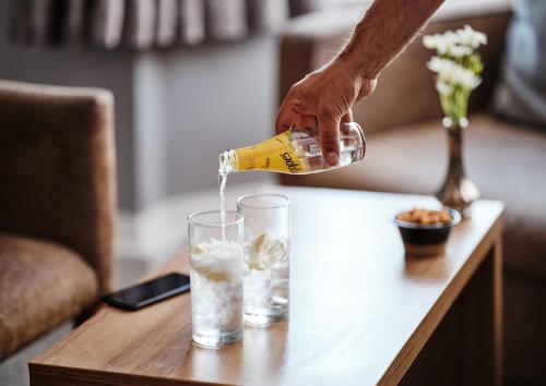 a person pouring a drink into a glass on a table at Linton Lodge a BW Signature Collection Hotel in Oxford