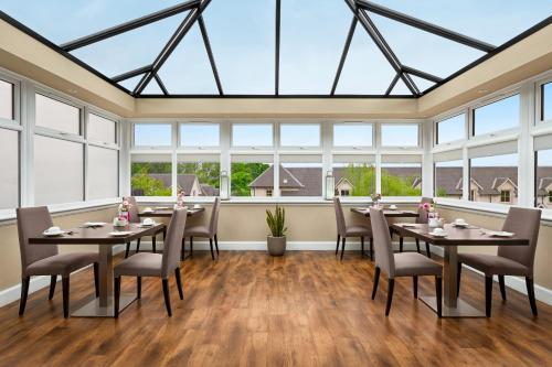 a dining room with tables and chairs and windows at Wyndham Duchally Country Estate in Auchterarder