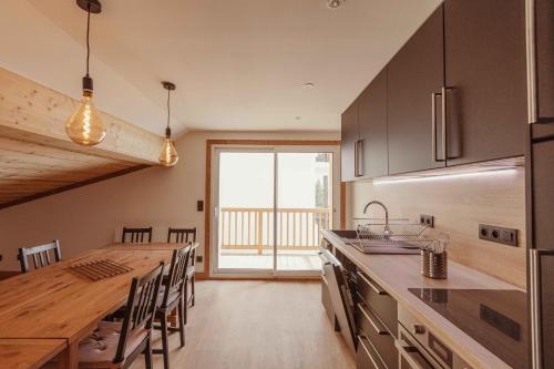 une cuisine avec une grande table en bois et une grande fenêtre dans l'établissement Le Chenaillet, duplex au pied des pistes et spa, à Montgenèvre