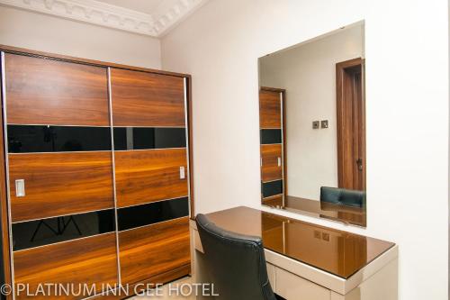 Suru LereにあるPlatinum Inn Gee Hotelのデスクと大きなガラスのキャビネットが備わる客室です。