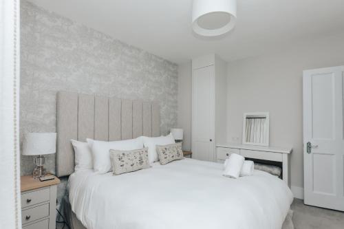 ein weißes Schlafzimmer mit einem großen weißen Bett mit Kissen in der Unterkunft The Dragonfly - Central 2 bedroom house in Henley on Thames