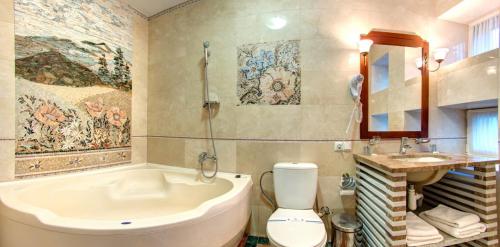 a bathroom with a tub and a toilet and a sink at LAVANDA country club in Tatariv