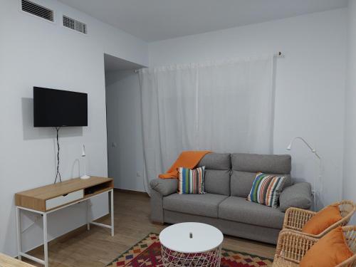 een woonkamer met een bank en een tv bij Orange Suite by Alhaurín Loft City Center in Alhaurín de la Torre
