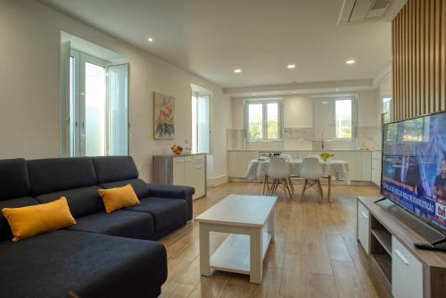 a living room with a couch and a flat screen tv at Flor de Valença Guest House in Valença
