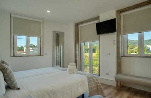 - une chambre avec 2 lits et 2 fenêtres dans l'établissement Alojamento da Vila - Apartamentos, à Valença