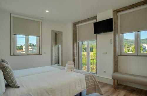 una camera da letto con due letti e due finestre di Flor de Valença Guest House a Valença