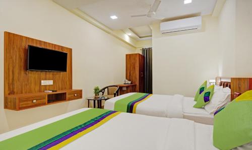 a bedroom with two beds and a tv on the wall at Tripli Hotels Le Shelton in Udaipur