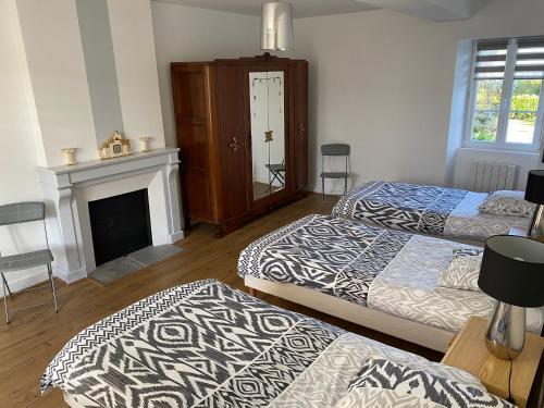 - un salon avec deux lits et une cheminée dans l'établissement La Barberie à Saint-Marcouf, à Saint-Marcouf