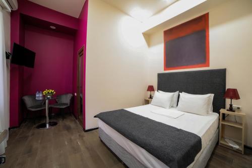 una habitación de hotel con una cama grande y una mesa en Elysium Gallery Hotel, en Ereván