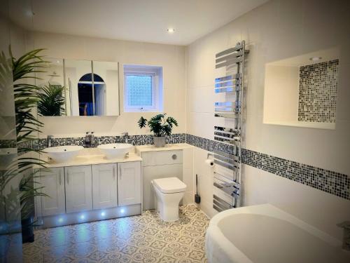 a white bathroom with two sinks and a toilet at Kingsfield House by Cliftonvalley Apartments in Bristol