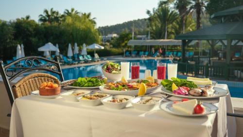 una mesa con platos de comida junto a una piscina en Green Bay Resort & Spa - All Inclusive, en Guvercinlik