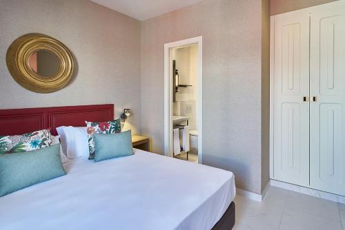 a bedroom with a large white bed with blue pillows at Vincci Molviedro Suites Apartments in Seville