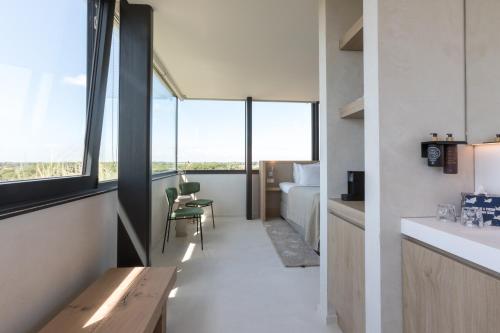 a room with a kitchen and a bedroom with windows at Duinhotel Tien Torens in Zoutelande