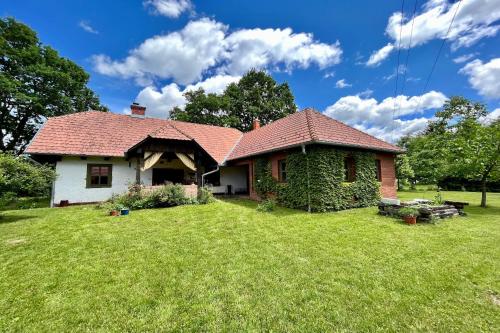 una casa blanca con techo rojo en un patio en Őrségi Mi Kis Házunk vendégház, en Szalafő