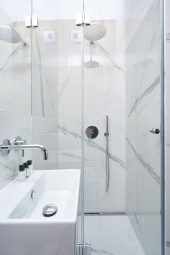 a white bathroom with a shower and a sink at Apartamenty Olimpijska by RENT4YOU in Olsztyn