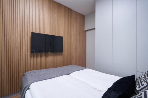 a bedroom with a bed and a flat screen tv on a wall at Apartamenty Olimpijska by RENT4YOU in Olsztyn