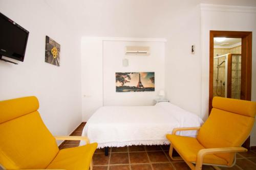 a bedroom with two yellow chairs and a bed at Apartamentos Turisticos Trajano in Bolonia