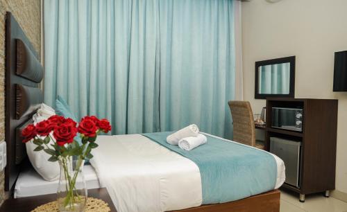 a bedroom with a bed with a vase of red roses at Bayside Hotel Pietermaritzburg in Pietermaritzburg