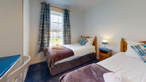 une chambre avec deux lits et une fenêtre dans l'établissement Dingle Harbour Cottages 3 Bed - Sleeps 6 Type A by Trident Holiday Homes, à Dingle