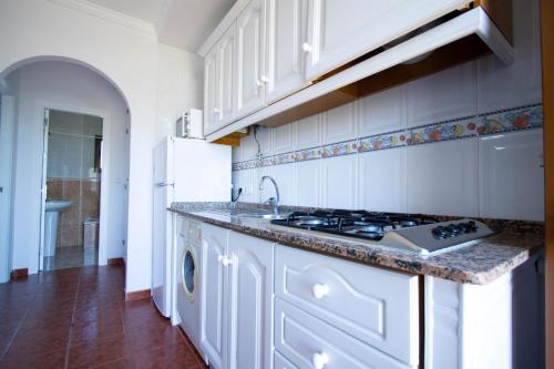 a kitchen with white cabinets and a sink and a stove at Apartamentos Turisticos Trajano in Bolonia