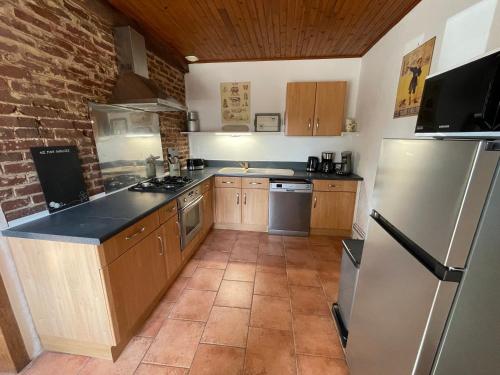 une cuisine avec des placards en bois et un mur en briques dans l'établissement Beaurepaire Gîte entre Terre et Mer, à Heudelimont