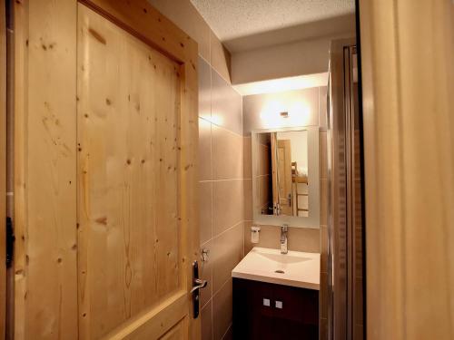 La salle de bains est pourvue d'un lavabo et d'une porte en bois. dans l'établissement Studio rénové 4 pers, ski aux pieds, Les Menuires - 21m², 2 Flocons Or, Accès direct pistes. - FR-1-178-364, aux Menuires
