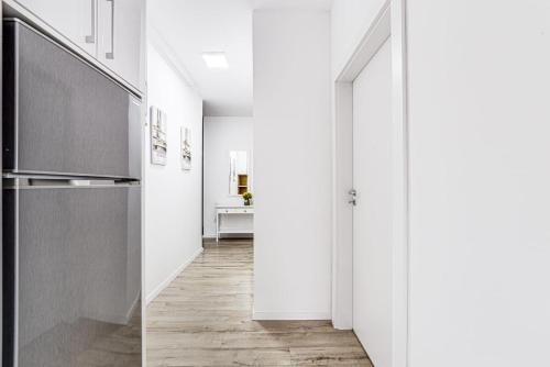 a hallway with white walls and a kitchen with wood floors at ARI GREEN Apartment near Atrium Mall in Arad