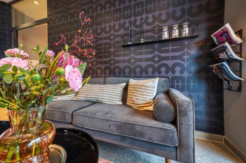 a living room with a couch and a vase of flowers at Vienna House Easy by Wyndham Hannover in Hannover