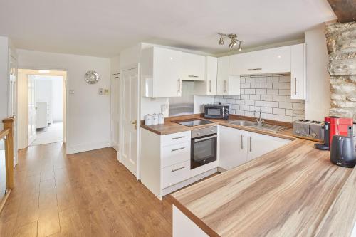 a kitchen with white cabinets and a wooden floor at Host & Stay - The Duck Pond in Durham