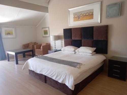 ein Schlafzimmer mit einem großen Bett und einem Stuhl in der Unterkunft Mount Royal 31 - Large 1 bed with balcony in Johannesburg