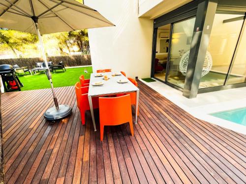 a wooden deck with a table and chairs and an umbrella at Villa PAM, ALYA Beach House with pool and Hot Tub in Alcudia
