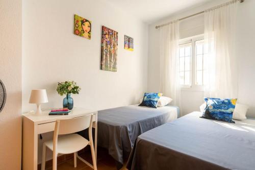 a room with two beds and a desk and a table at Apartamento centro Rota. 2 minutos de la playa.. in Rota