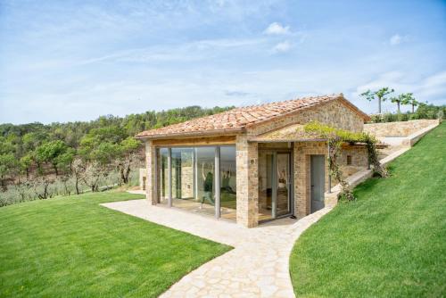 a stone house with glass doors on a grassy field at The Club House in Castelnuovo Berardenga