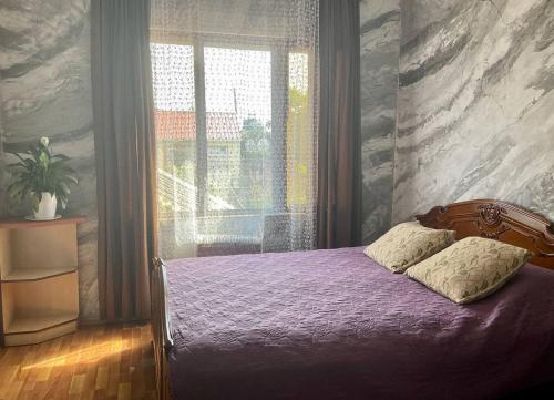 een slaapkamer met een paars bed en een raam bij Bagrationi 54 in Kobuleti