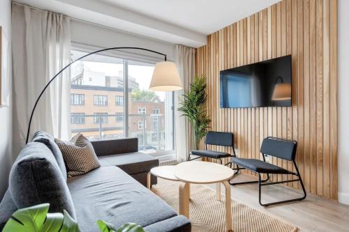 een woonkamer met een bank, een tafel en een tv bij INITIAL / ARTWOOD / Centre-ville de Quebec in Québec