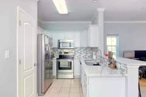 una cocina con armarios blancos y electrodomésticos de acero inoxidable en Spacious Home, Short Walk to Beach, Heated Pool! en Corpus Christi