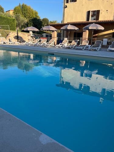 a swimming pool with chairs and umbrellas at Apartments Colombara Bardolino in Bardolino