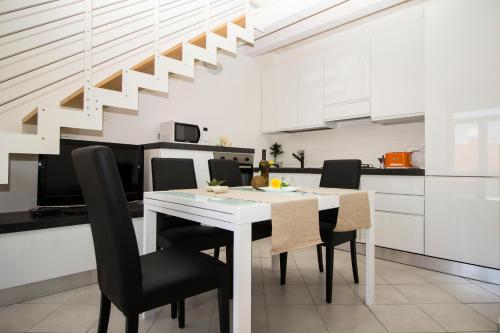 une salle à manger avec une table blanche et des chaises noires dans l'établissement InnPisaRentals - Charme Pisa Toscana 1, à Pise