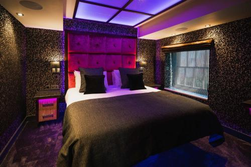 um quarto com uma cama grande e iluminação roxa em Church Suites by The Cranleigh Boutique em Bowness-on-Windermere