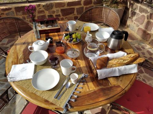 een houten tafel met borden en bekers en een fruitschaal bij Le palmier d'Alice in Collonges