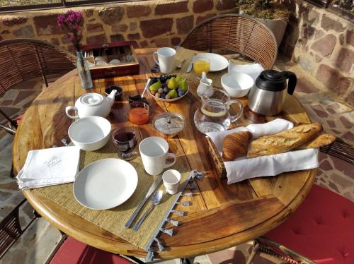 - une table en bois avec des assiettes, des tasses et un bol de fruits dans l'établissement Le palmier d'Alice, à Collonges