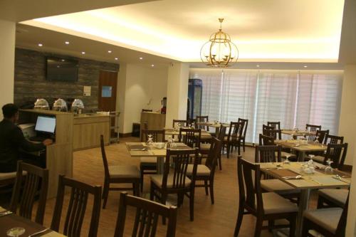 a restaurant with tables and chairs and a man sitting at a counter at Priyo Nibash Stylish Residential Hotel in Dhaka